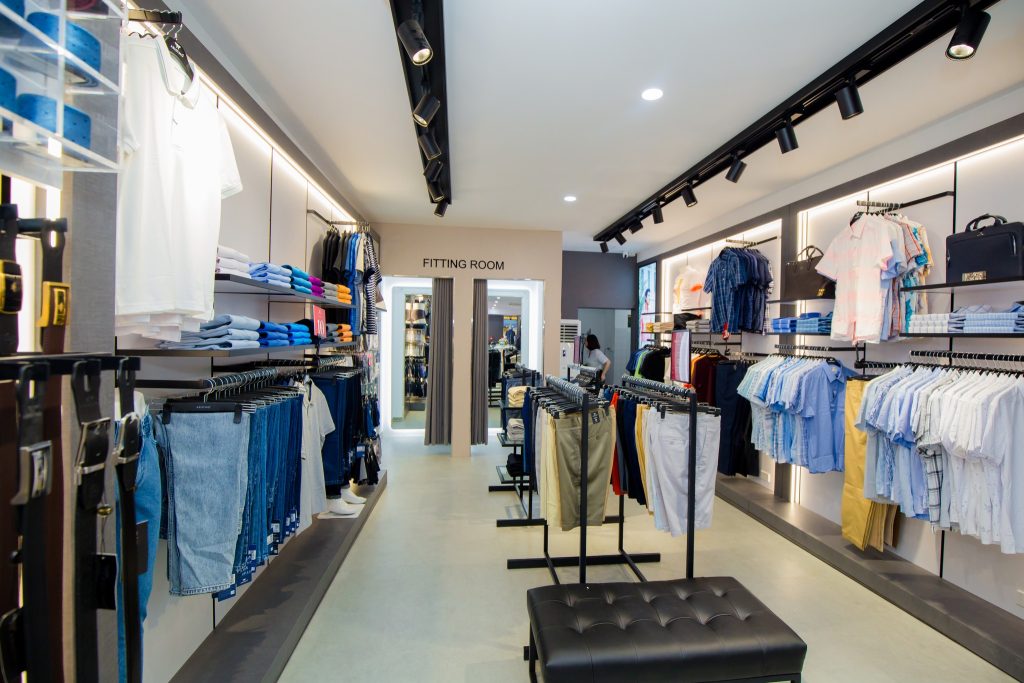 Cửa hàng thời trang nam sáng sủa với quần jean và áo — cộng tác viên bán quần áo nam