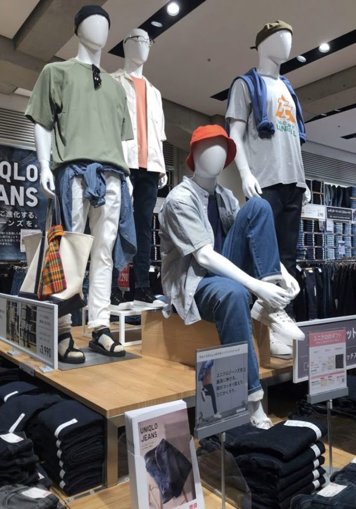 Ma-nơ-canh mặc áo thun nam nhiều màu gồm màu olive bên kệ jeans — nhập sỉ áo thun nam